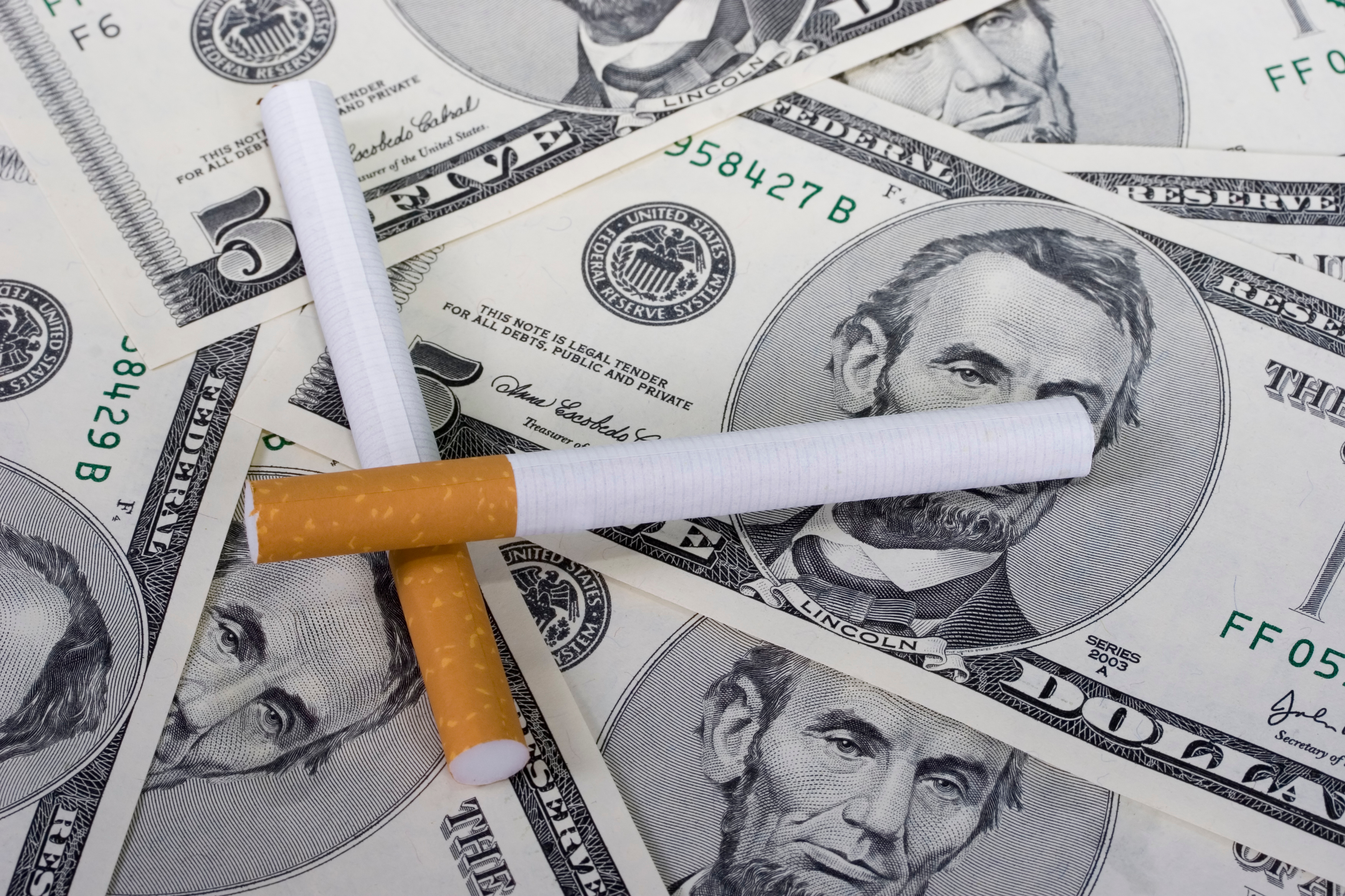 Stock image of cigarettes on top of cash. 