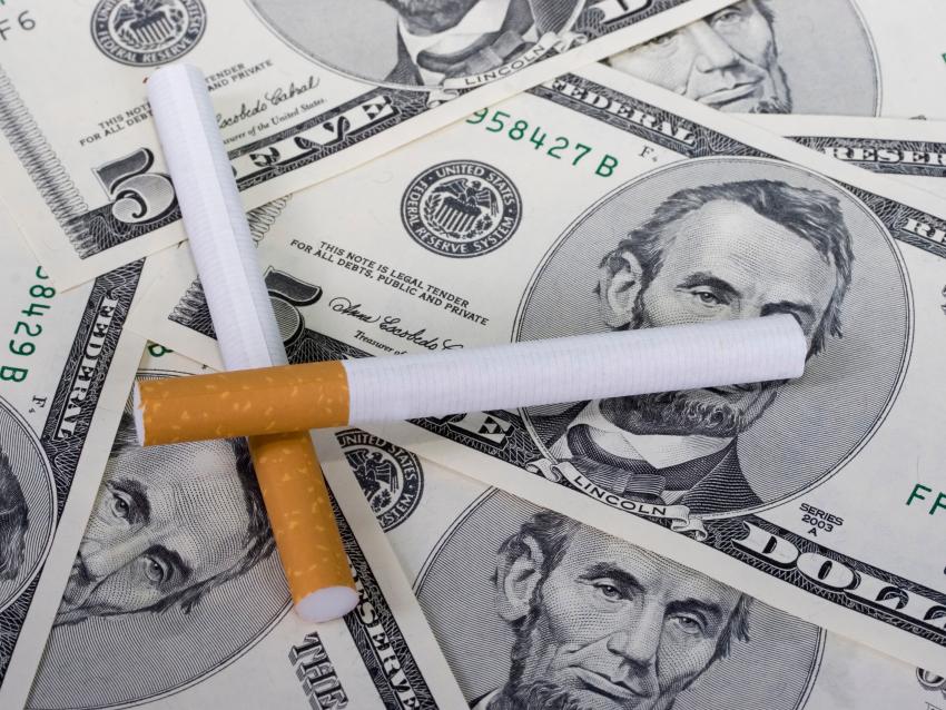 Stock image of cigarettes on top of cash.